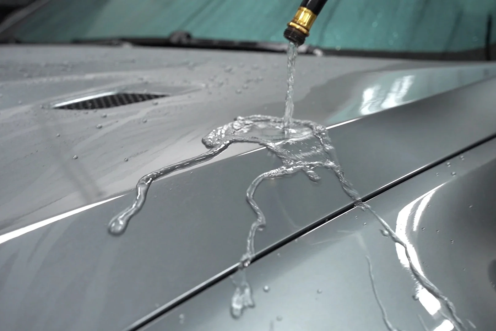 Water beading and rolling off a ceramic coated car surface